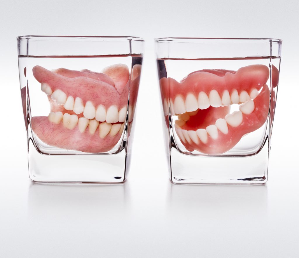 2 pairs of dentures in glasses with water